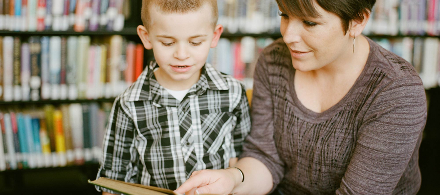Een vrouw leest voor uit een boek aan een kind.