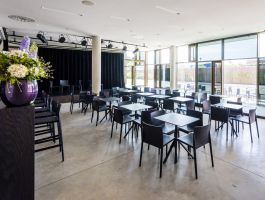 Foyer met tafeltjes, stoelen en podium